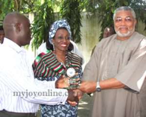 Anthony Corsy, Lecturer in Mass Communication at the Kaduna State University presents the plaque to Mr  Mrs Rawlings